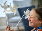 Image of lady smiling with 3 decorated windmills in her hand