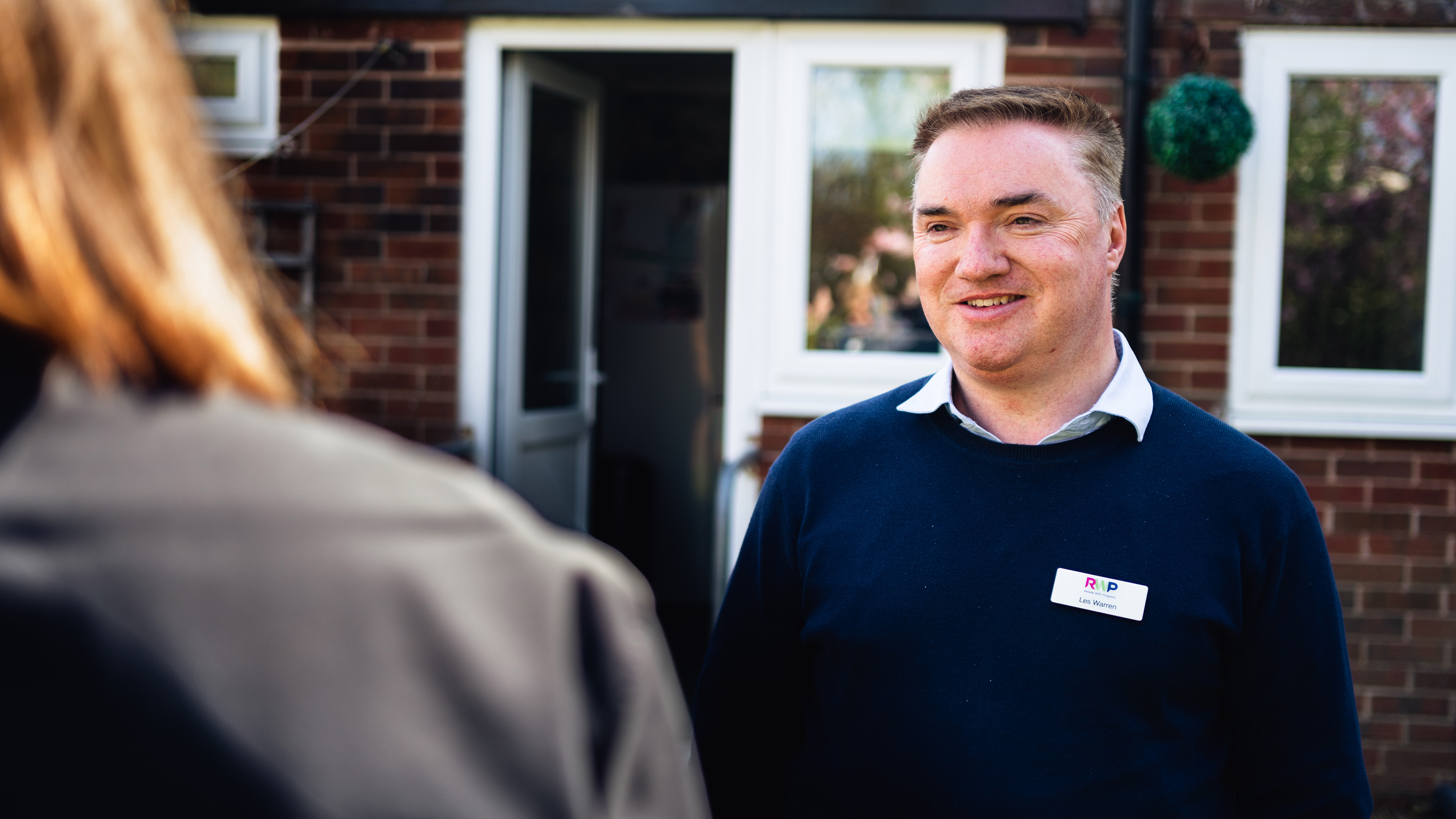 Man smiling and talking to a woman