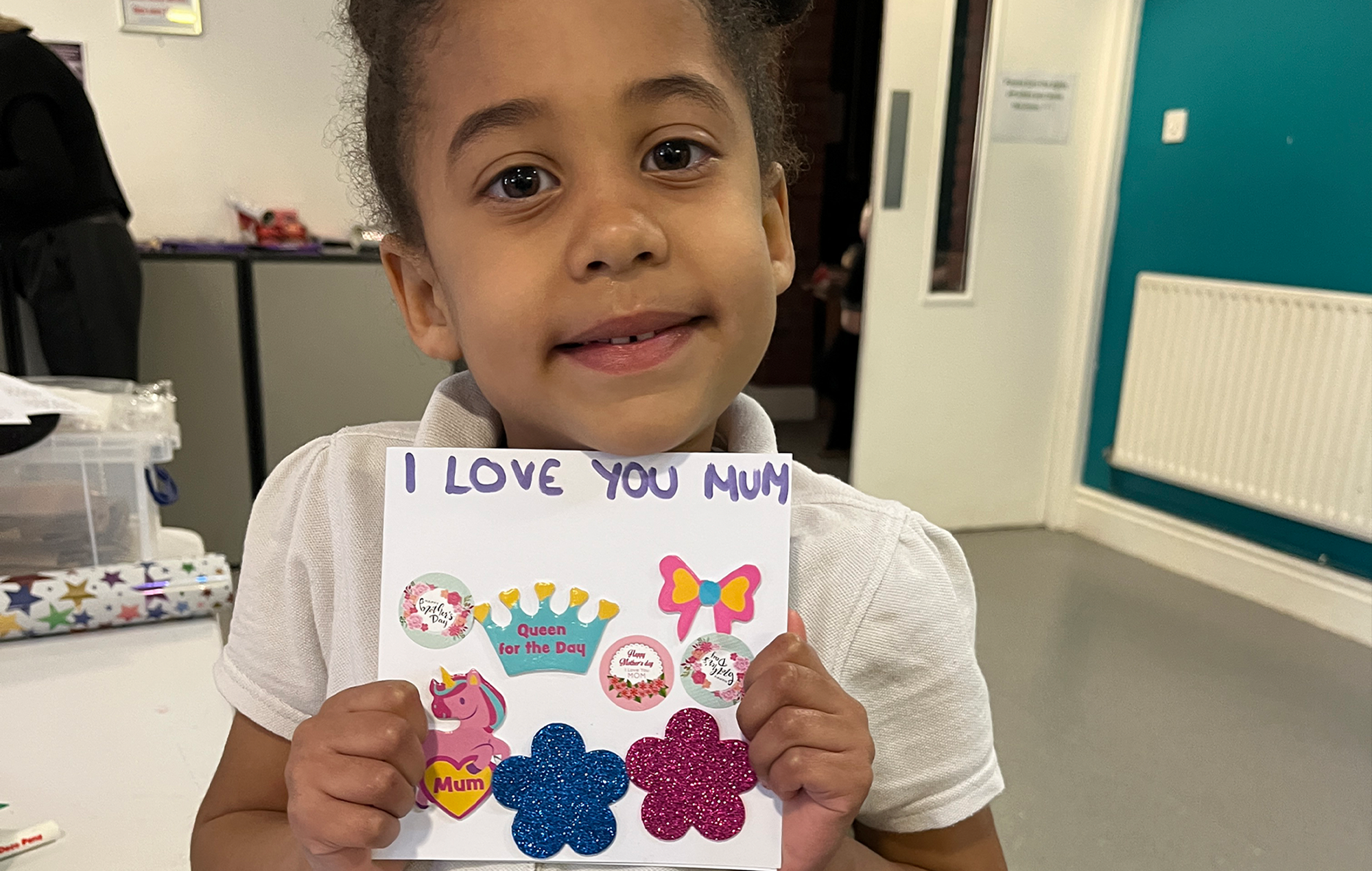 Young girl holding card she has hand made for her mother