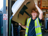 Trades operative carrying a bath tub above his head laughing 