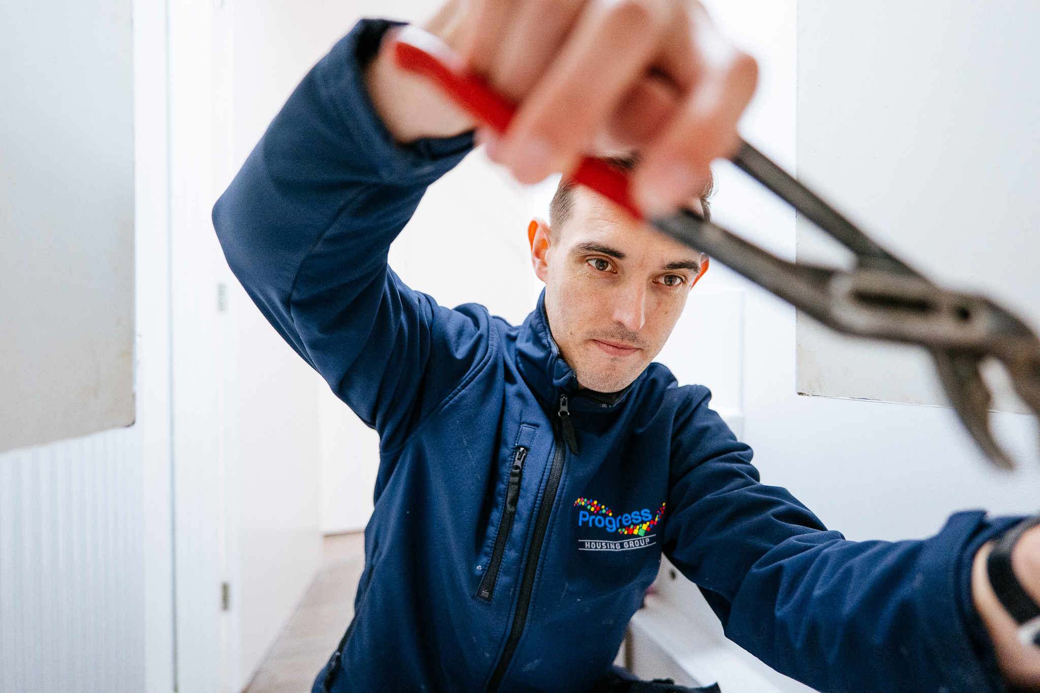 Progress Housing Group repairs team member doing a repair with a wrench in a tenant’s home