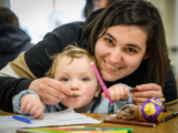 Image of lady and young child eating easter egg and colouring