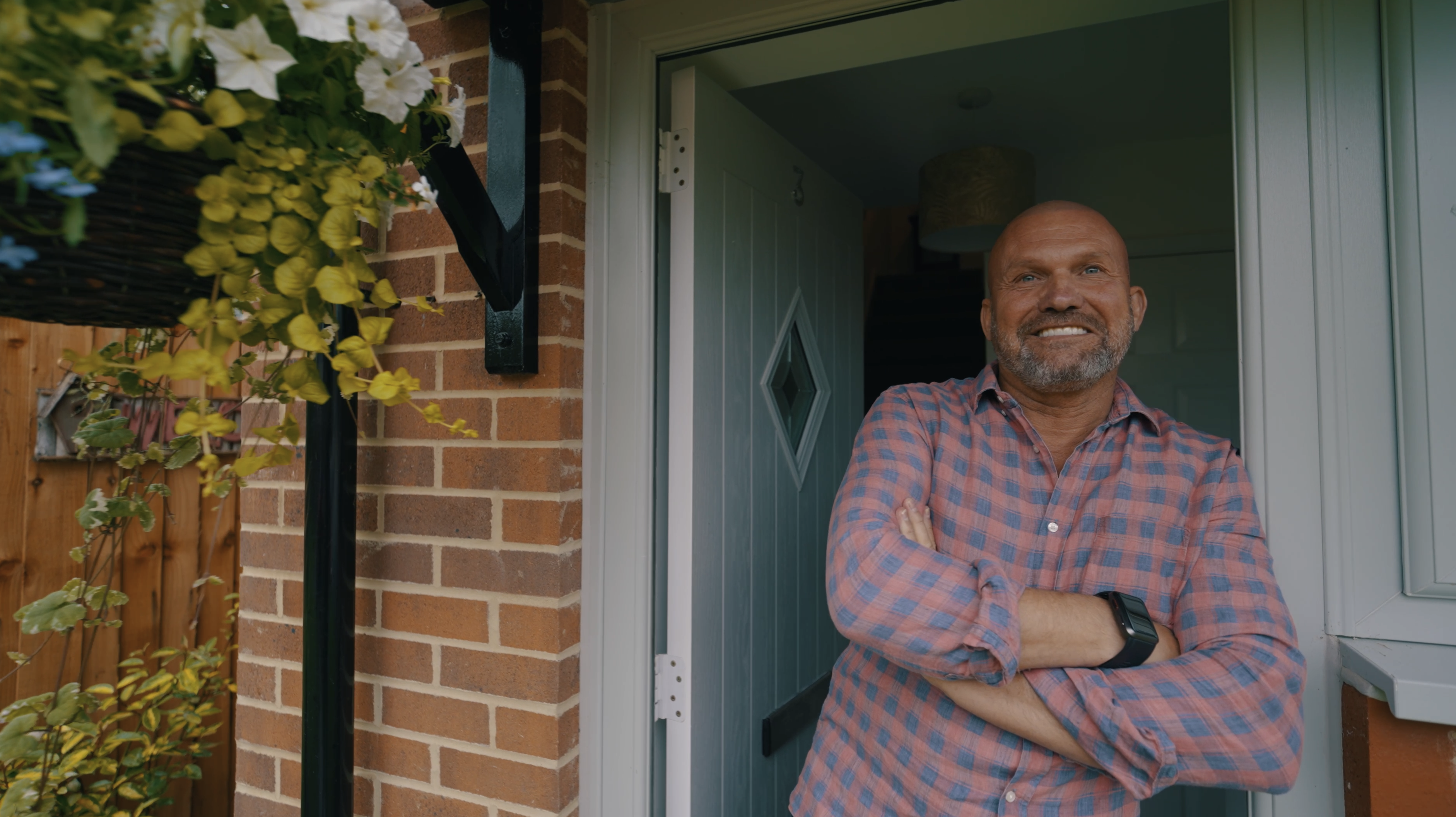 Image of a man stood at the front door of his house