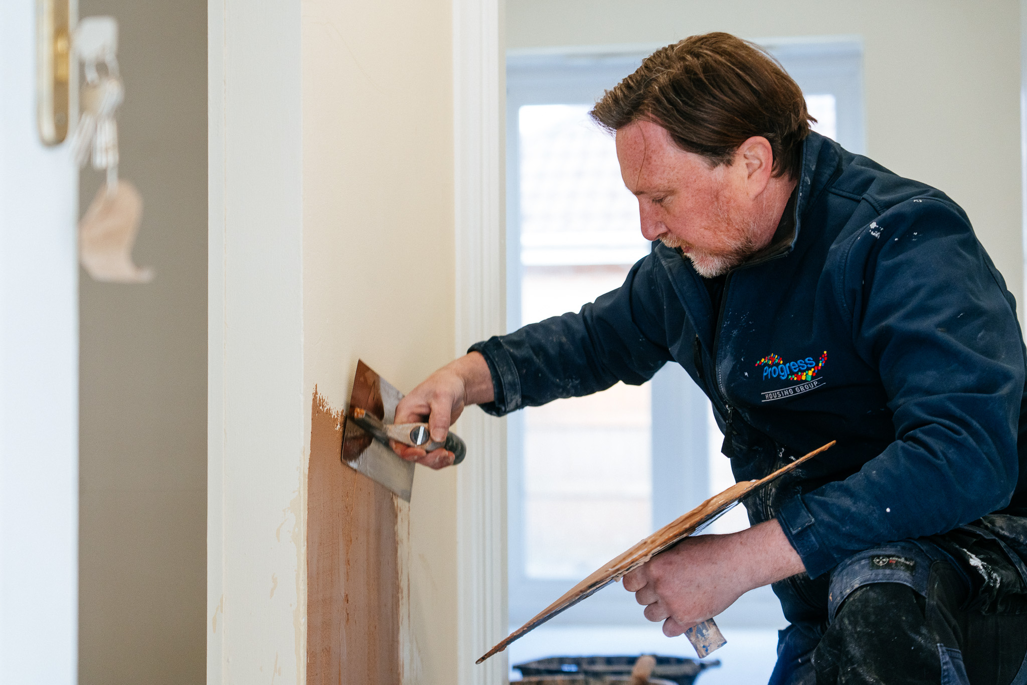 Progress Housing Group repairs team member plastering a wall in a tenant’s home