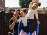 Lady and her 2 children smiling enjoying the sunshine on their garden slide