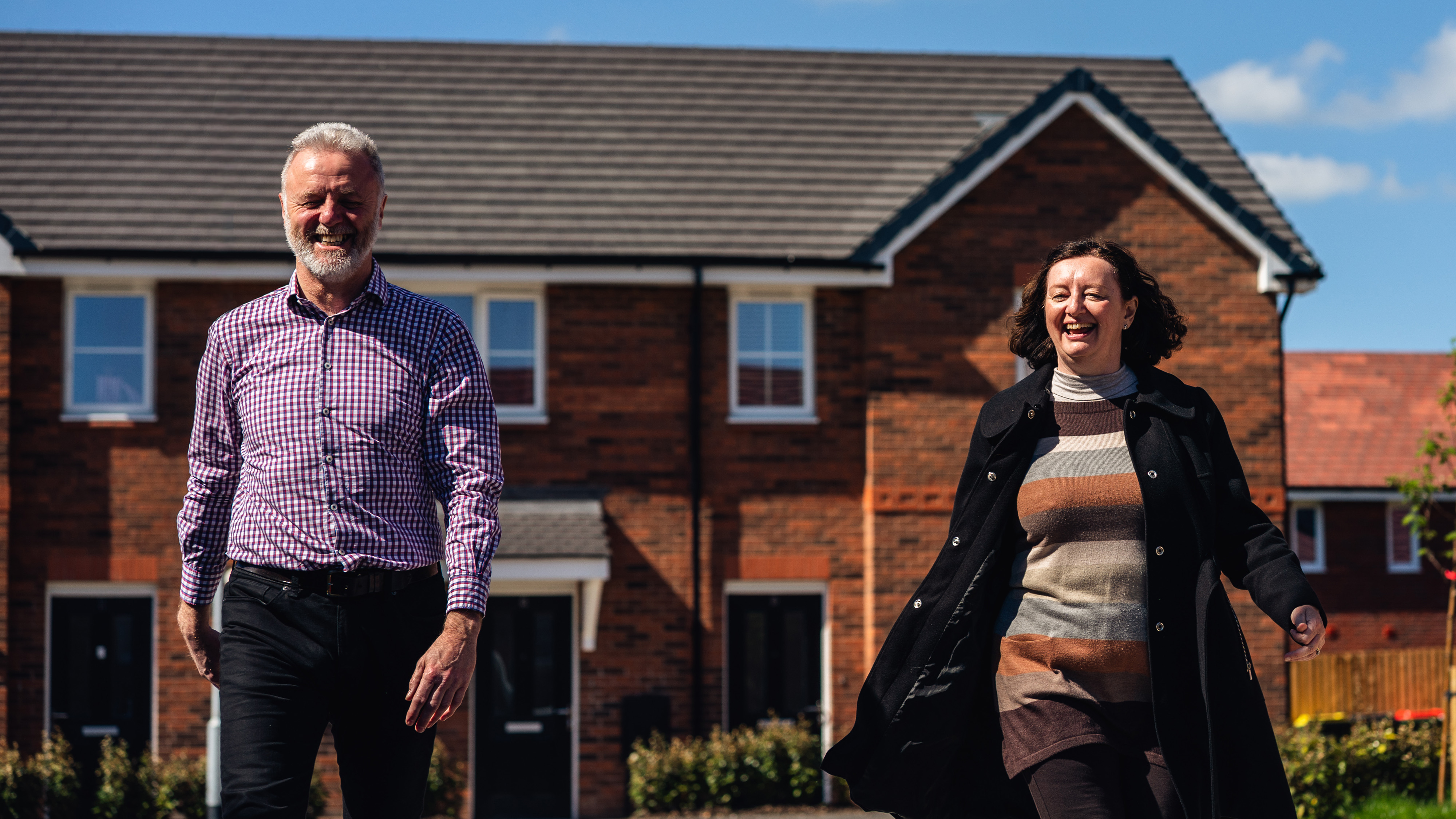 Man and woman with positive smiles with Progress homes in the background